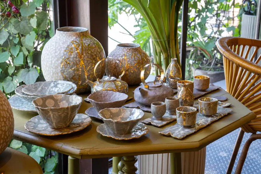 Earth-toned ceramic bowls and vases displayed with plants