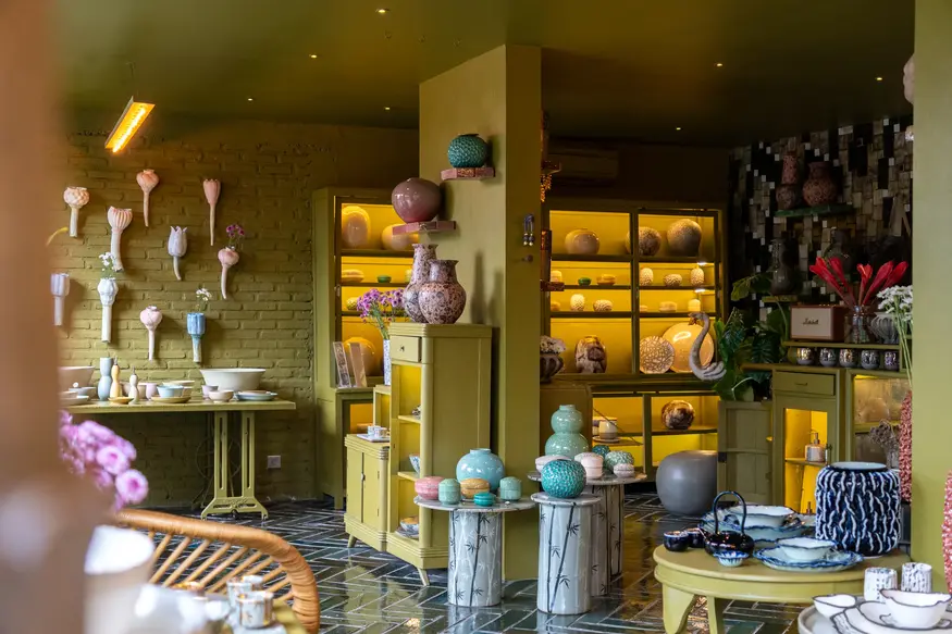 Interior of the Gaya Ceramic showroom with olive-green shelving full of colourful ceramics
