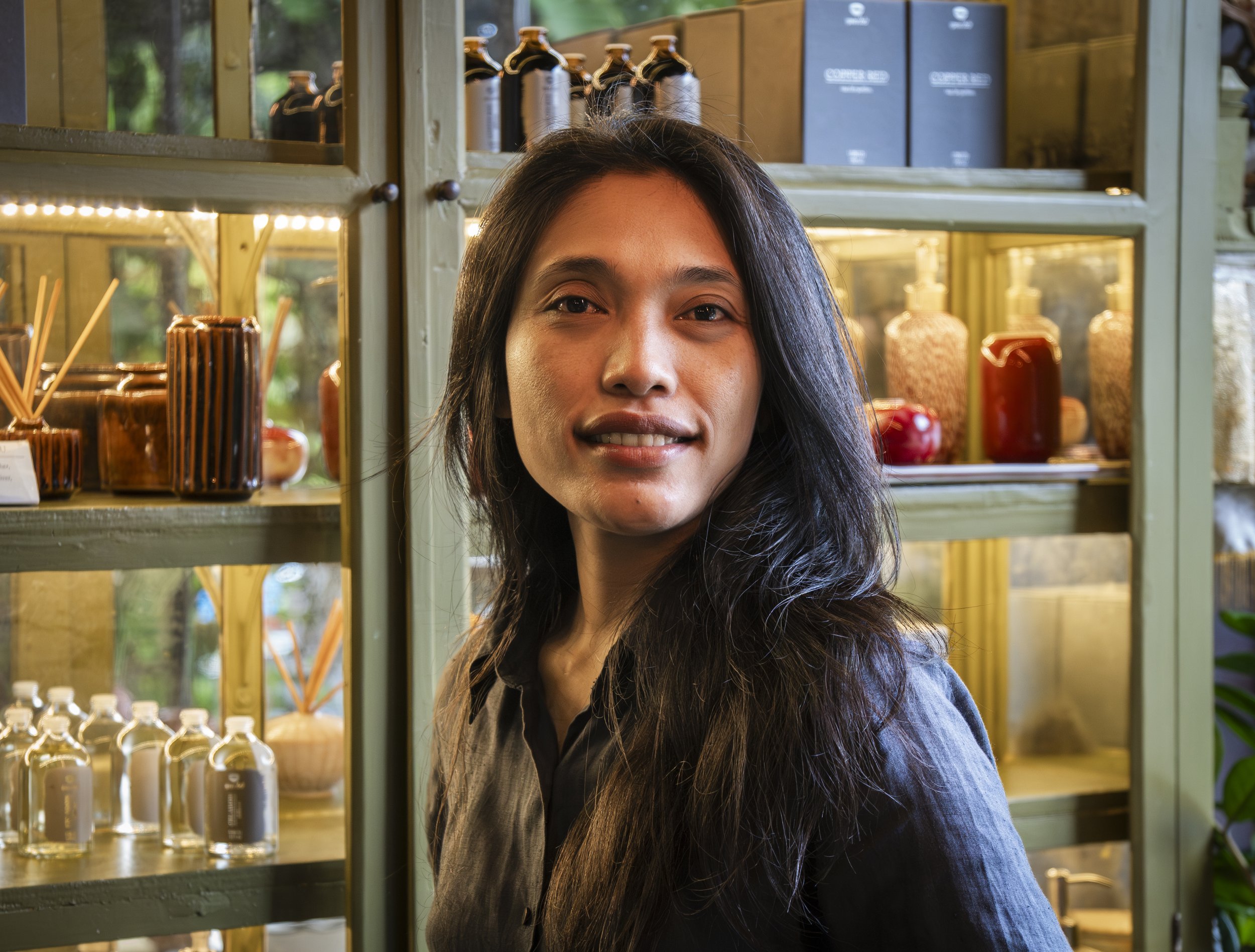 Portrait of a Gaya Ceramic team member by shelves of finished ceramics