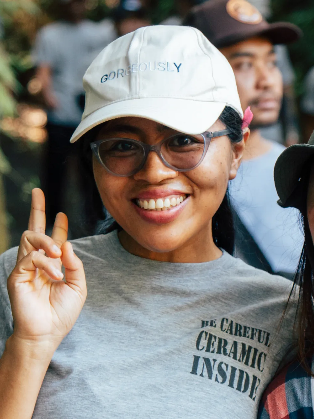 Smiling Gaya Ceramic team member in glasses and a cap giving a peace sign