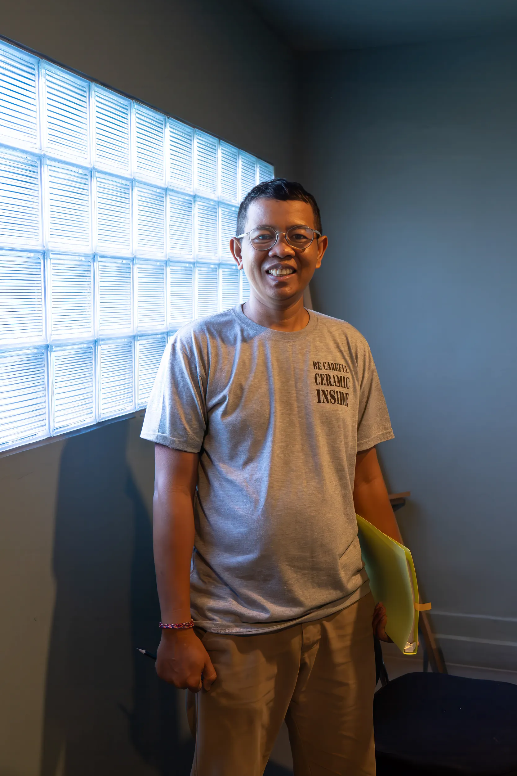 Gaya Ceramic team member standing by a glass-block window in the studio office